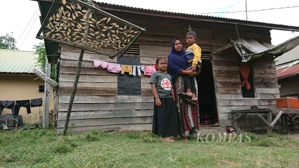Halimatul Sadiah (25) dan kedua anaknya saat berada di rumahnya di Desa Lambada Lhok, Kecamatan Baitussalam, Kabupaten Aceh Besar, Aceh, Kamis (10/3/2022). Suaminya, Nasrol Hamni, seorang nelayan tradisional, hilang saat melaut dan hingga kini belum ditemukan. Halimah kerluarga miskin yang mengandalkan JKN untuk kebutuhan berobat.