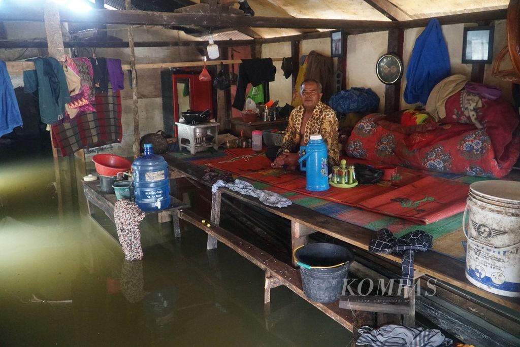 Warga duduk di papan darurat di dalam rumahnya yang terendam banjir akibat meluapnya Batang Merao di Desa Tanjung, Kecamatan Hamparan Rawang, Kota Sungai Penuh, Jambi, Sabtu (20/1/2024). 