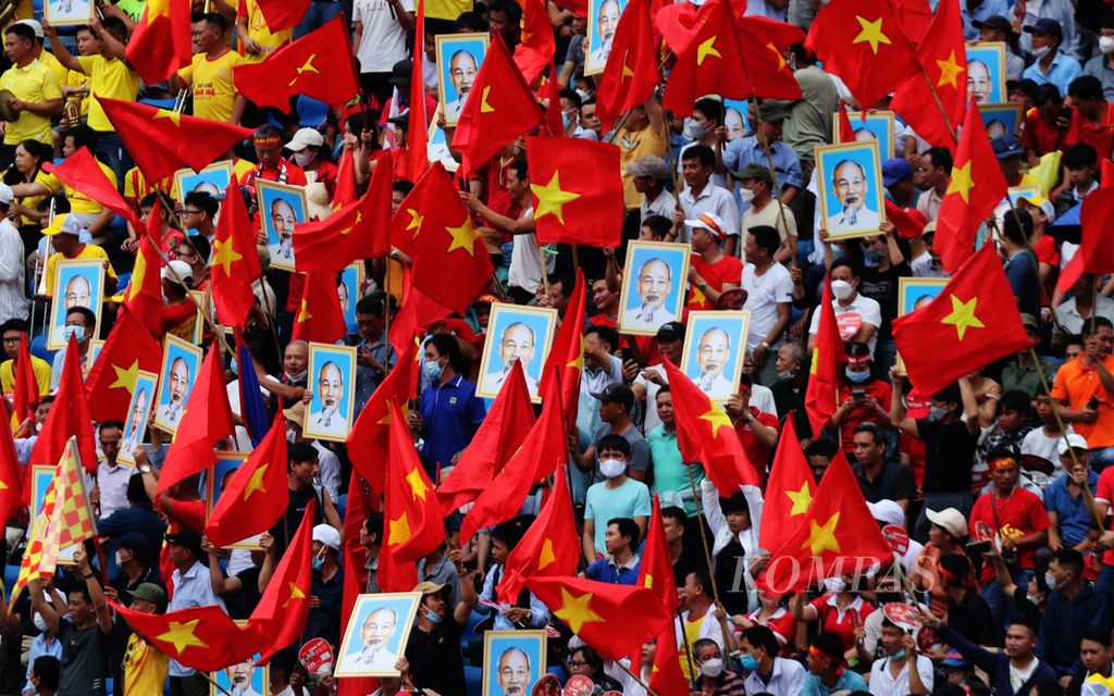 Ratusan warga bernyanyi dan membawa sejumlah poster bergambar tokoh Ho Chi Minh di Stadion Thien Truong, Nam Dinh, Vietnam, untuk menyaksikan laga pertandingan sepakbola yang bertepatan dengan perayaan hari kelahiran tokoh tersebut, Kamis (19/5/2022).  