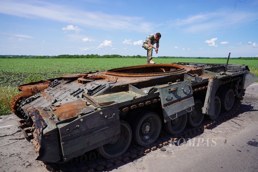 Anggota pertahanan teritorial melihat tank Rusia yang hancur di tepi jalan di Provinsi Sumy, Ukraina, Minggu (26/6/2022). Dalam beberapa hari terakhir, Rusia mengintensifkan serangan rudal ke Ukraina. Wilayah Ukraina yang diserang pun meluas.