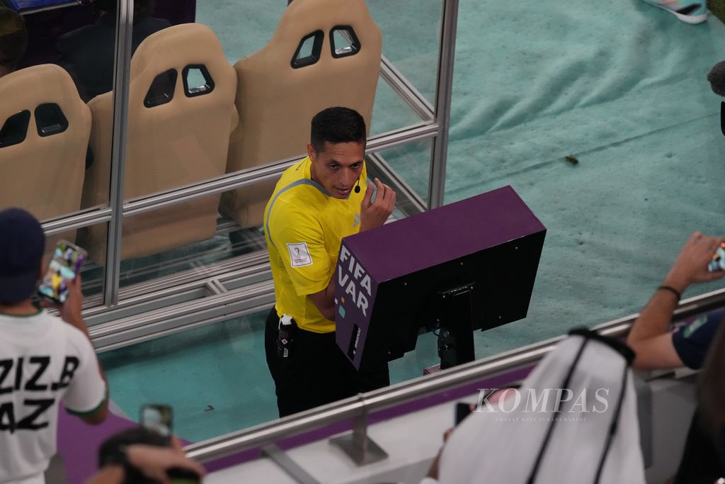 Referee Jesus Valenzuela checks the video assistant referee (VAR) screen before giving a penalty to Poland when facing France in the round of 16 match of the 2022 World Cup at Al Thumama Stadium, Qatar, Sunday (4/12/2022). France advanced to the quarter-finals after beating Poland 3-1.