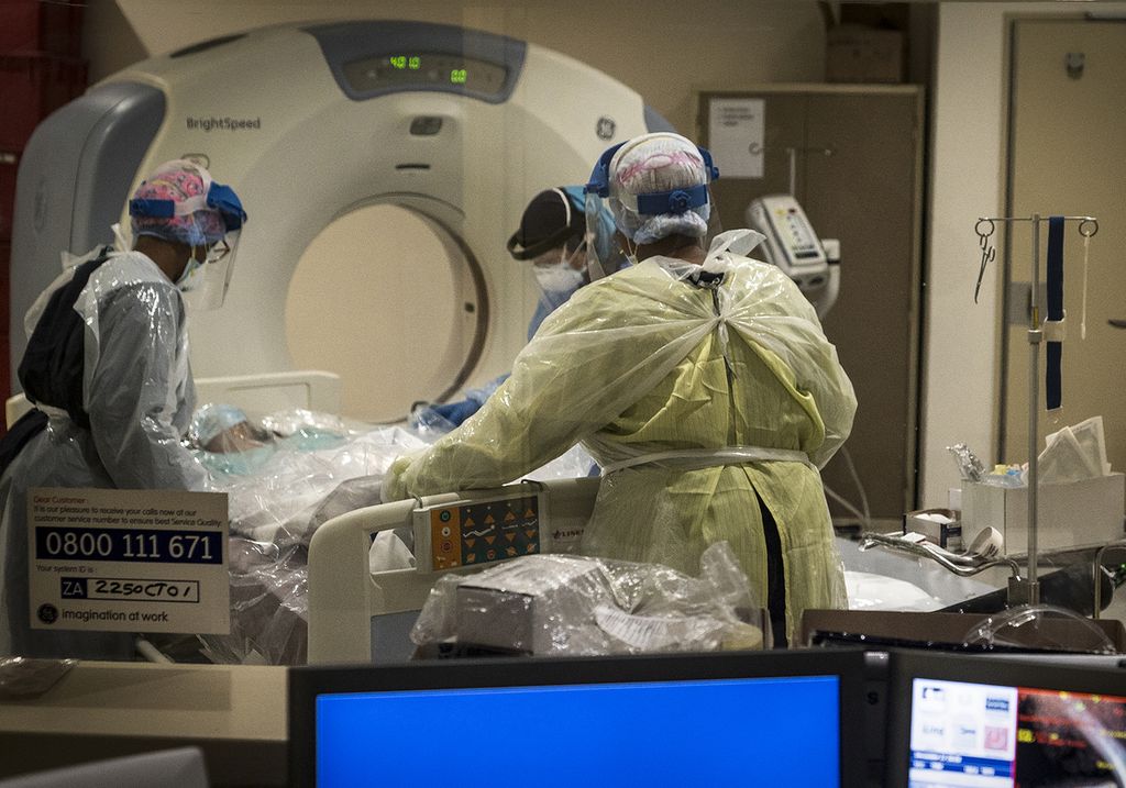 Petugas medis mempersiapkan pasien positif Covid-19 untuk menjalani CT-<i>scan </i>di sebuah klinik di Johannesburg, Minggu (27/12/2020).