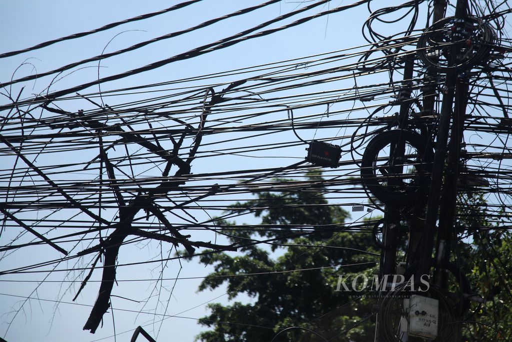 Batang kayu tersangkut pada kabel utilitas di Jalan Kebayoran Lama, Kebayoran, Jakarta Selatan, Selasa (1/8/2023).