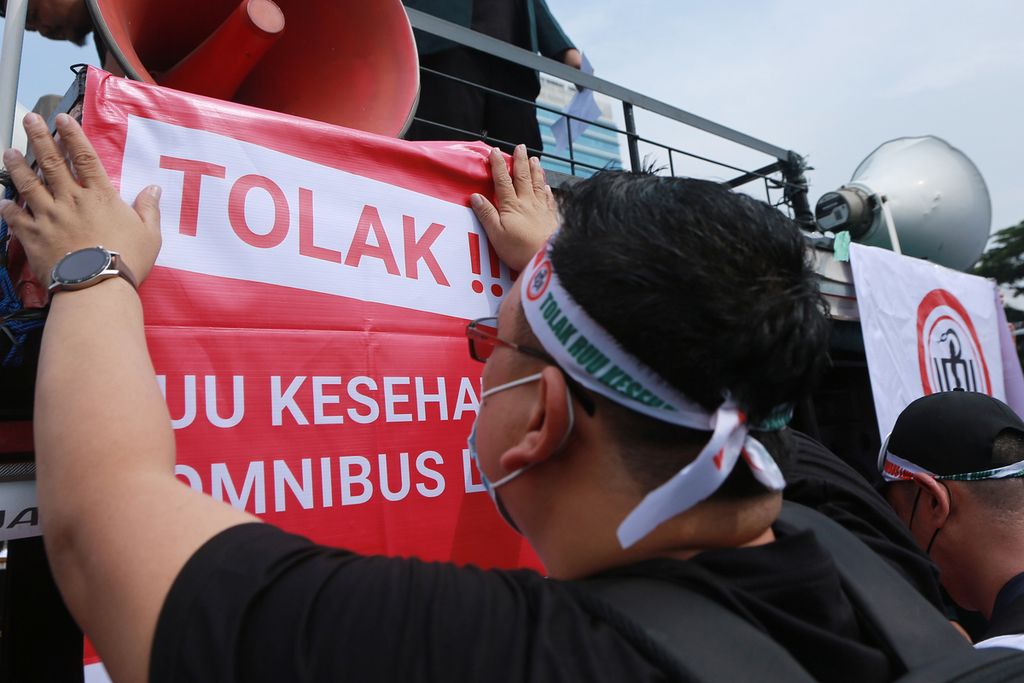 Tenaga kesehatan memasang spanduk aksi di mobil komando saat aksi demo tolak RUU Kesehatan di depan Gedung DPR, Jakarta, Senin (28/11/2022). 