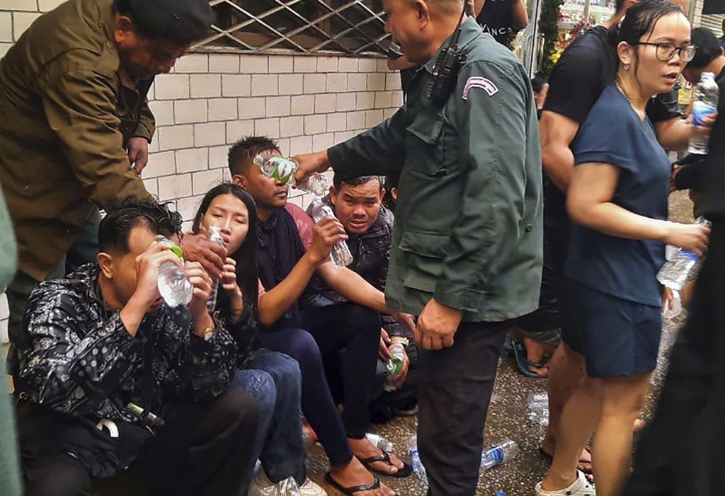 Dalam foto yang disediakan media Fresh News Kamboja ini, para korban kebakaran menerima air dari petugas polisi di dekat gerbang perbatasan internasional Kamboja-Thailand di Kota Poipet, sebelah barat Phnom Penh, Kamboja, Rabu (28/12/2022). Api membakar Grand Diamond City dan menewaskan 20 orang. 
