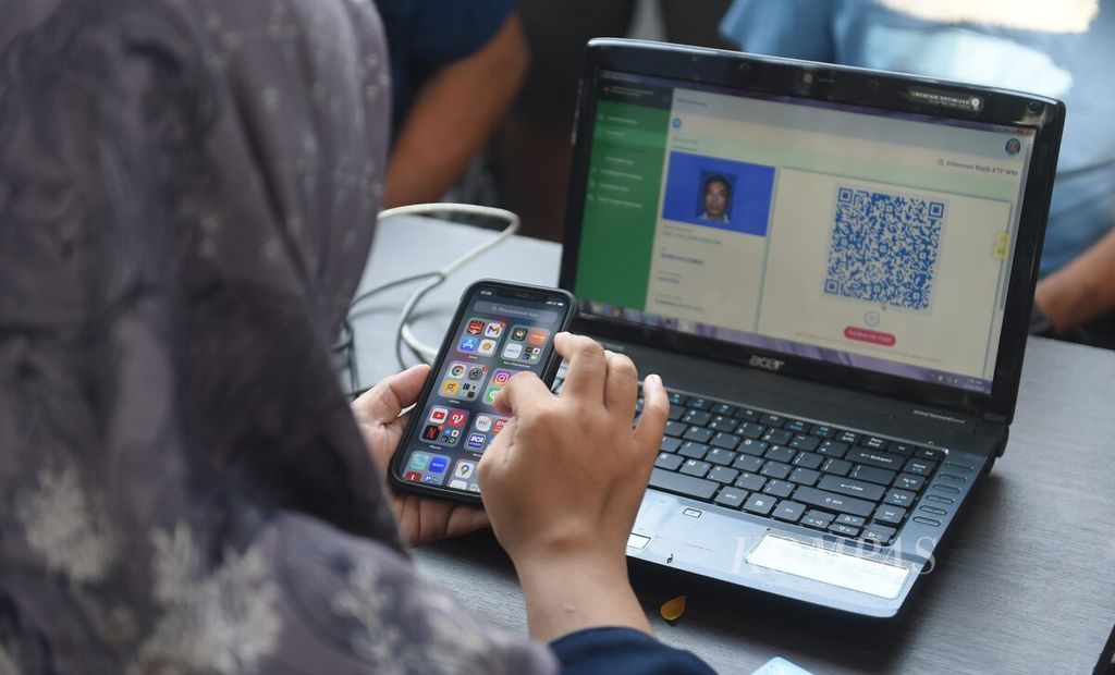 Petugas membantu warga mengurus Identitas Kependudukan Digital di gerai keliling Dinas Kependudukan dan Catatan Sipil Kota Surabaya di Jalan Darmo, Surabaya, Minggu (10/12/2023).