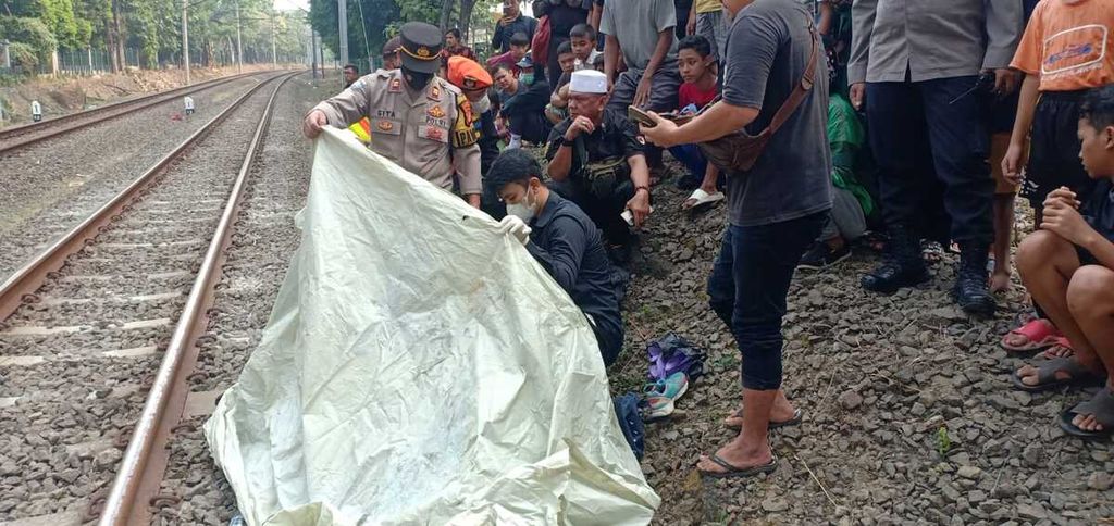 Polisi dan warga menengok jasad korban kecelakaan kereta, Rubiyanti (57), di sekitar Jalan Patal Senayan, Kelurahan Grogol Utara, Kecamatan Kebayoran Lama, Jakarta Selatan, Jumat (1/9/2023) siang.