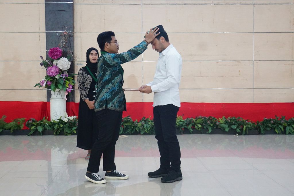 Radinal Muhdar (27) memakaikan peci ke kepala Ali (27) sebagai tanda pelantikannya sebagai Ketua Himpunan Mahasiswa Islam Cabang Manado di Graha Gubernuran, Manado, Sulawesi Utara, 18 Maret 2023. Radinal adalah Ketua HMI Cabang Manado periode 2021-2023, sementara Ali akan menjabat selama 2023-2024.