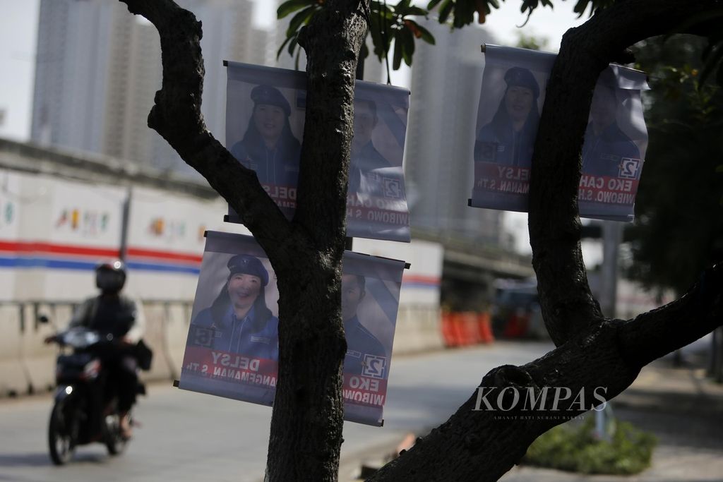 Alat peraga kampanye terpasang di pohon dengan cara memakunya, di Jalan RE Martadinata, Jakarta, Minggu (14/1/2024).