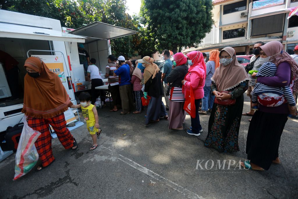 Seorang ibu kelluar dari antrean setelah membeli bahan makanan saat badan usaha milik daerah, PT Food Station Tjipinang Jaya, menggelar penjualan pangan murah di halaman kantor Kelurahan Pondok Kelapa, Kecamatan Duren Sawit, Jakarta Timur, Rabu (2/3/2022). 