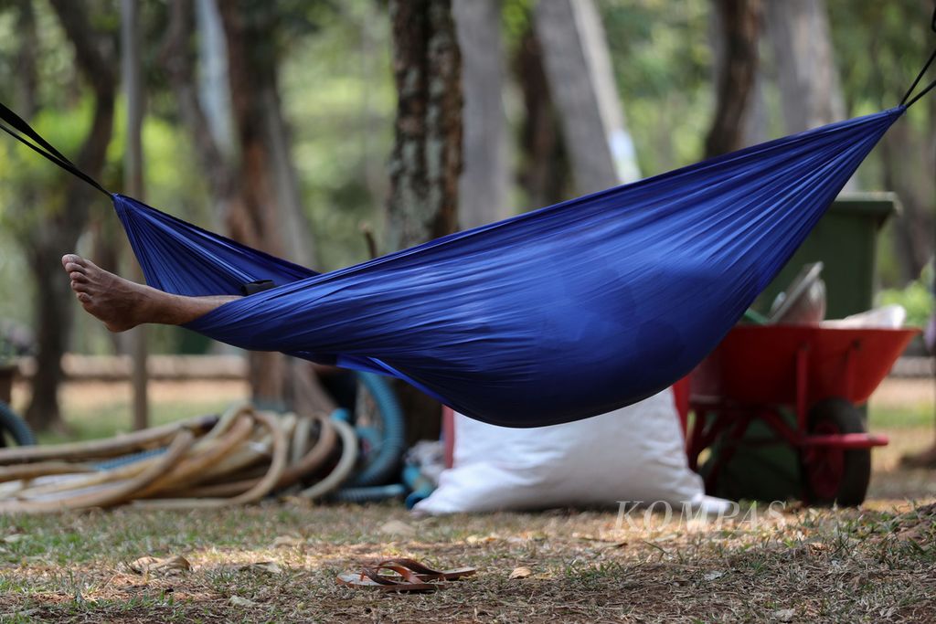 Warga tidur di atas <i>hammock</i> di Taman Cempaka, Jakarta Timur, Minggu (8/10/2023). Komunitas Ayo ke Taman menggelar acara Festival Taman dengan tema ”Ruang Sukaria, Ragam Berbudaya”. 