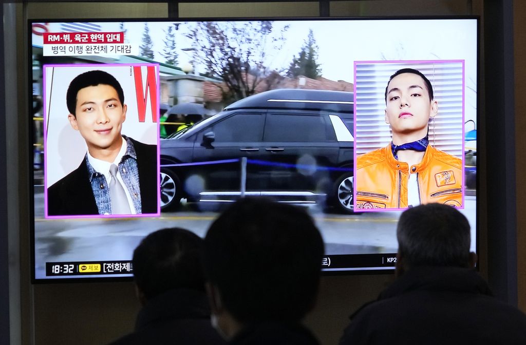 Layar TV menampilkan gambar RM (kiri) dan V, anggota band K-pop Korea Selatan, BTS, pada program berita di Stasiun Kereta Seoul, Seoul, Korsel, Senin (11/12/2023). RM dan V memulai tugas wajib militer sesuai hukum Korsel. 