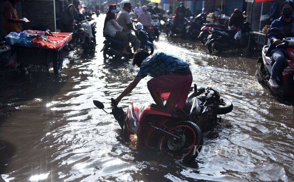 Pengendara sepeda motor terjatuh di genangan air akibat banjir luapan Kali Buntung di Jalan Kolonel Sugiono, Sidoarjo, Sabtu (5/3/2022).