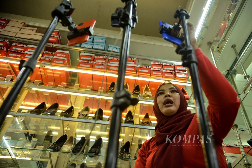 Traders interact with viewers on the Tiktok social media platform while offering their merchandise online through a live broadcast at the Block A Tanah Abang market in Jakarta on Tuesday (13/6/2023).