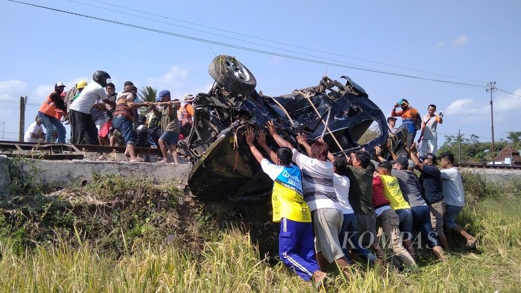 Warga bergotong royong mengevakuasi minibus yang baru terlibat kecelakaan dengan Kereta Penataran di Dusun Kebonsari, Desa Ngebruk, Kecamatan Sumberpucung, Kabupaten Malang, Jawa Timur, Kamis (9/10/2020).
