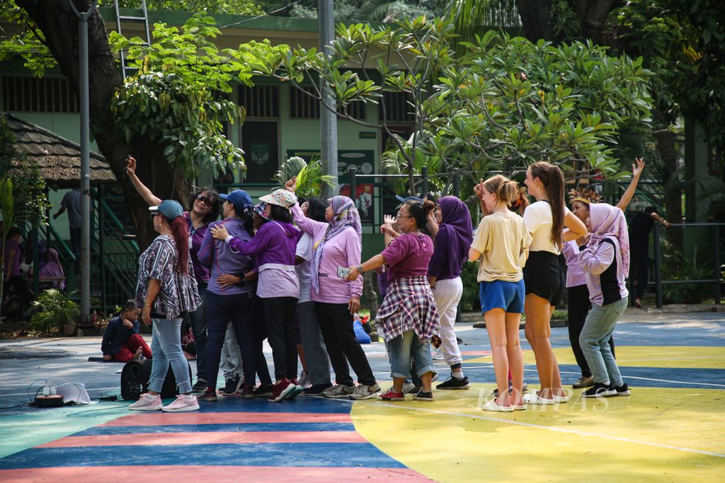 Kelompok ibu-ibu yang berlatih tari berswafoto dengan wisatawan mancanegara di Taman Menteng, Jakarta. Pusat, Kamis (22/6/2023). Taman kota menjadi tempat rekreasi murah bagi warga Ibu Kota.