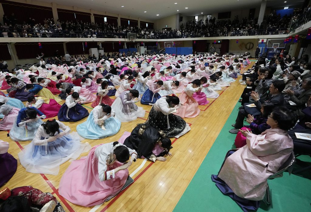 Anak-anak yang mengenakan pakaian tradisional membungkuk kepada guru dan orangtua saat upacara wisuda bersama dan kedewasaan di Sekolah Menengah Putri Dongmyung di Seoul, Korea Selatan, 6 Februari 2024.