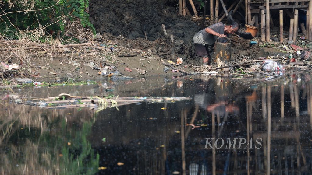 Warga mengeruk endapan lumpur Kali Bekasi yang tercemar berwarna hitam pekat di Margahayu, Kecamatan Bekasi Timur, Kota Bekasi, Jawa Barat, Selasa (19/9/2023). 