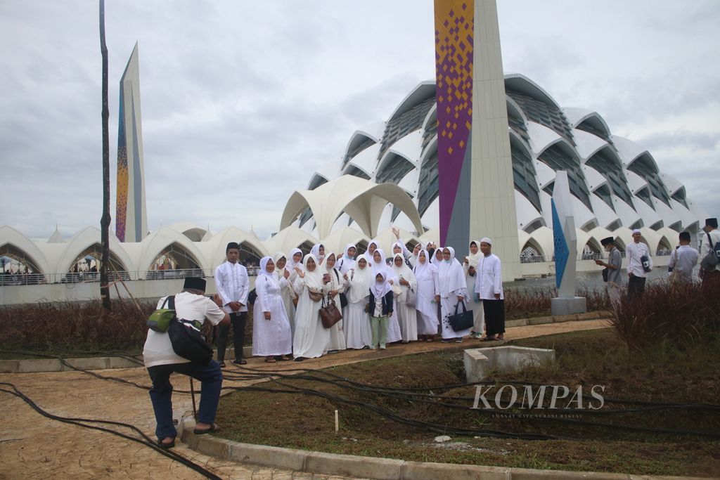 Warga berfoto bersama dengan latar belakang Masjid Raya Al Jabbar, Kecamatan Gedebage, Kota Bandung, Jawa Barat, saat peresmian masjid tersebut, Jumat (30/12/2022).