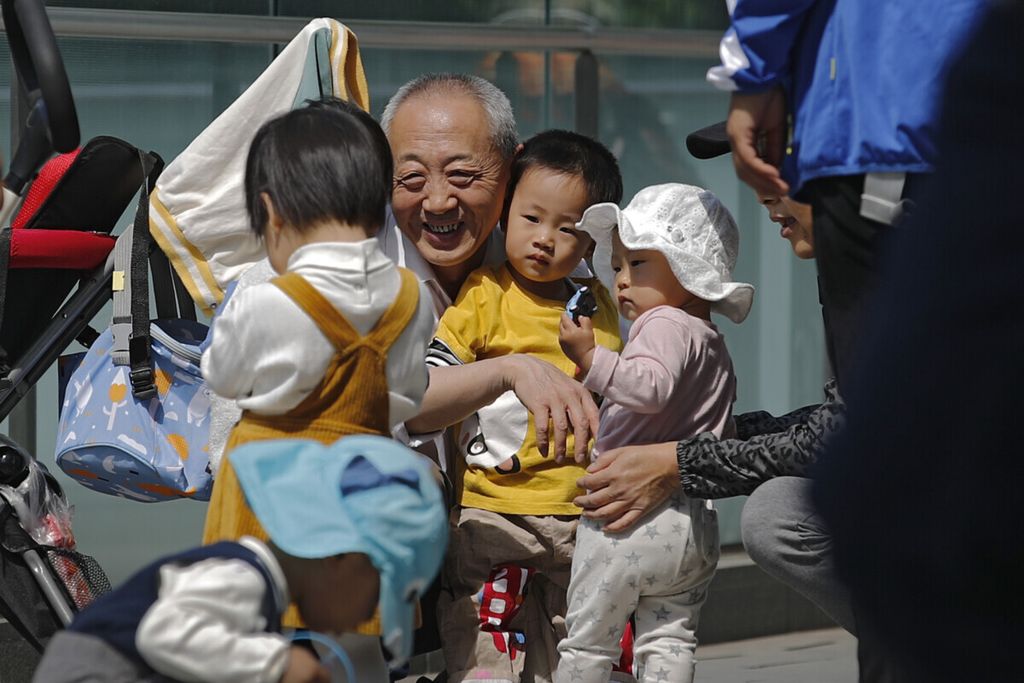 Seorang warga lanjut usia bermain dengan anak-anak di dekat gedung perkantoran komersial di Beijing, China, 10 Mei 2021. 