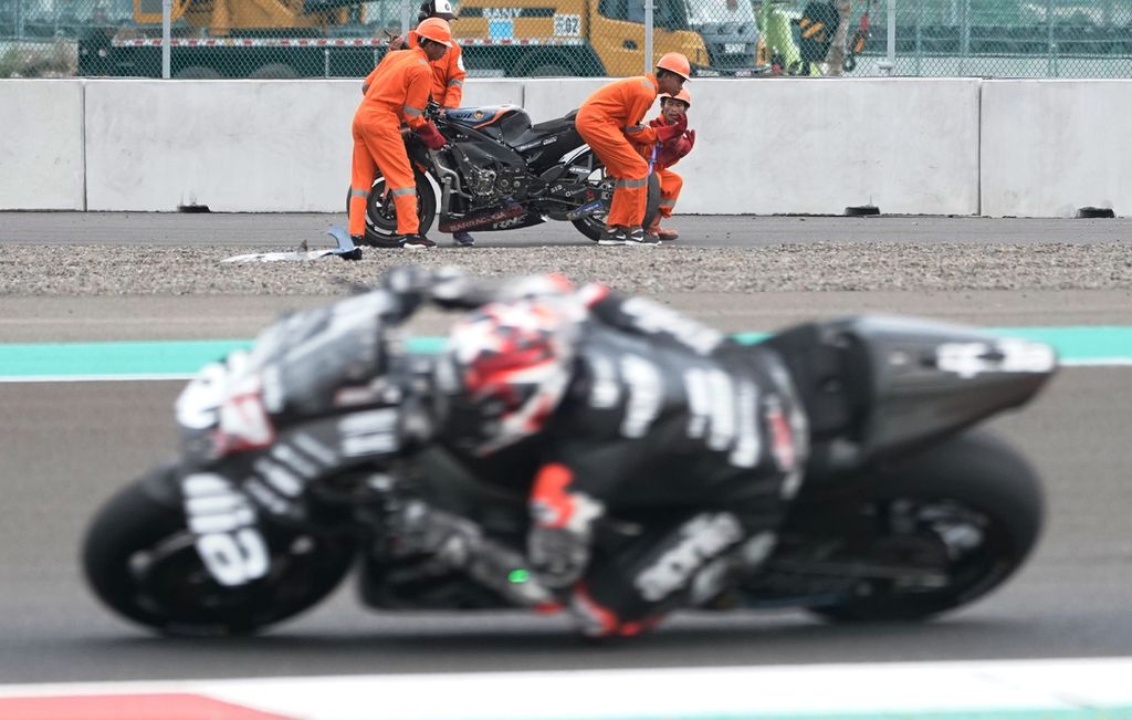 Petugas mengevakuasi motor pebalap MotoGP yang terjatuh di salah satu tikungan di Sirkuit Mandalika, Sabtu (12/02/2022). Debu dari pembangunan yang menutupi lintasan membuat sejumlah pebalap terjatuh pada hari kedua uji coba pramusim MotoGP.    