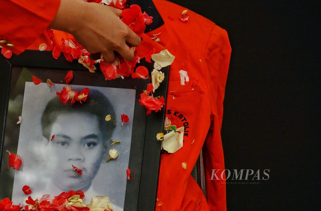 Ilustrasi. Tangan seorang mahasiswi Universitas Katolik Atmajaya menaburkan bunga pada foto potret Benardinus Realino Norma Irawan, mahasiswa Unika Atmajaya Senin (13/11/2023). Ia korban penembakan Tragedi Semanggi. 