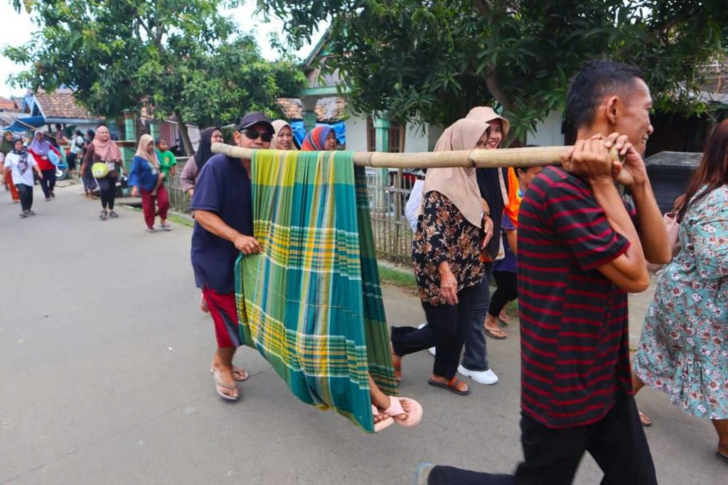 Warga menandu seorang warga lain saat simulasi evakuasi bencana untuk bersiap menghadapi potensi gempa <i>megathrust</i> Selat Sunda di Kabupaten Pandeglang, Banten, Kamis (5/9/2024).