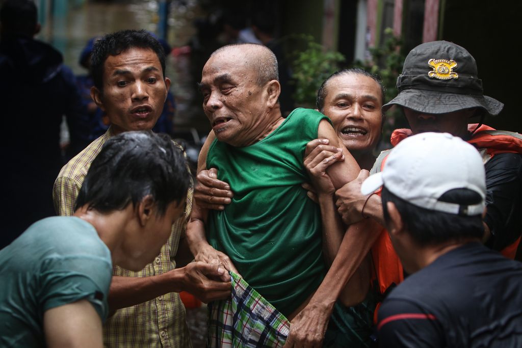 Warga mengevakuasi seorang warga lansia yang terjebak banjir di Kampung Melayu, Jatinegara, Jakarta Timur, Senin (27/2/2023). 