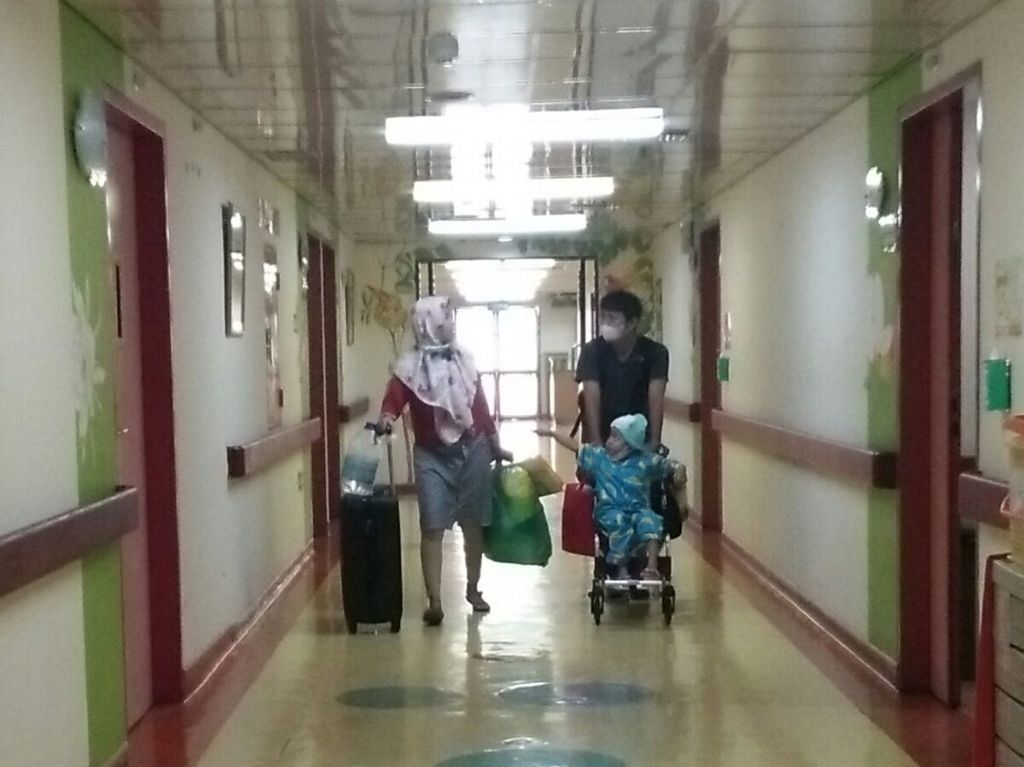 Seorang anak pasien kanker didampingi kedua orangtuanya melintasi lorong ruang rawat inap perawatan anak di Rumah Sakit Kanker Dharmais, Jakarta Barat, Rabu (14/2).