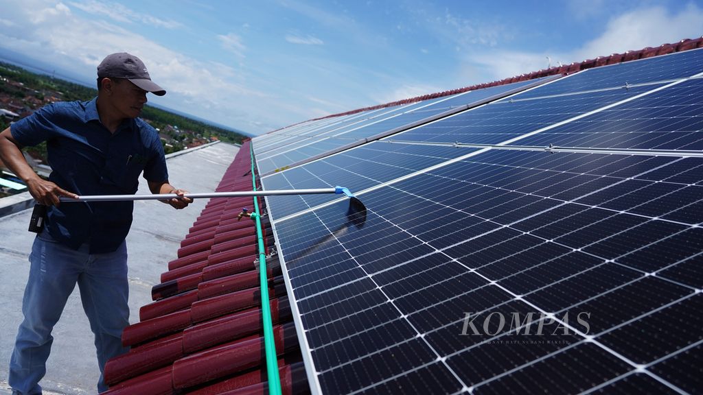 Pekerja membersihkan permukaan panel surya yang terpasang di atap Hotel Santika Banyuwangi, Banyuwangi, Jawa Timur, Minggu (11/9/2022). Penggunaan panel surya di tempat tersebut mampu menghemat penggunaan listrik konvensional  25 persen. Gerakan dukungan pariwisata hijau semakin meluas ke sektor-sektor akomodasi wisata, termasuk penggunaan panel surya di tempat penginapan-penginapan.