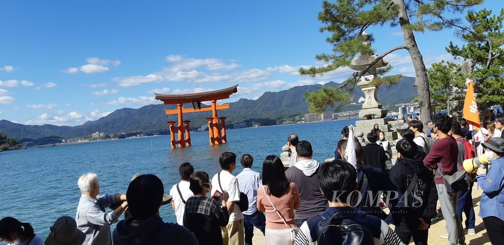 Turis berkerumun menyaksikan gerbang Torii menuju Kuil Itsukushima di Pulau Miyajima di selatan Hiroshima, Jepang, akhir Oktober 2023.