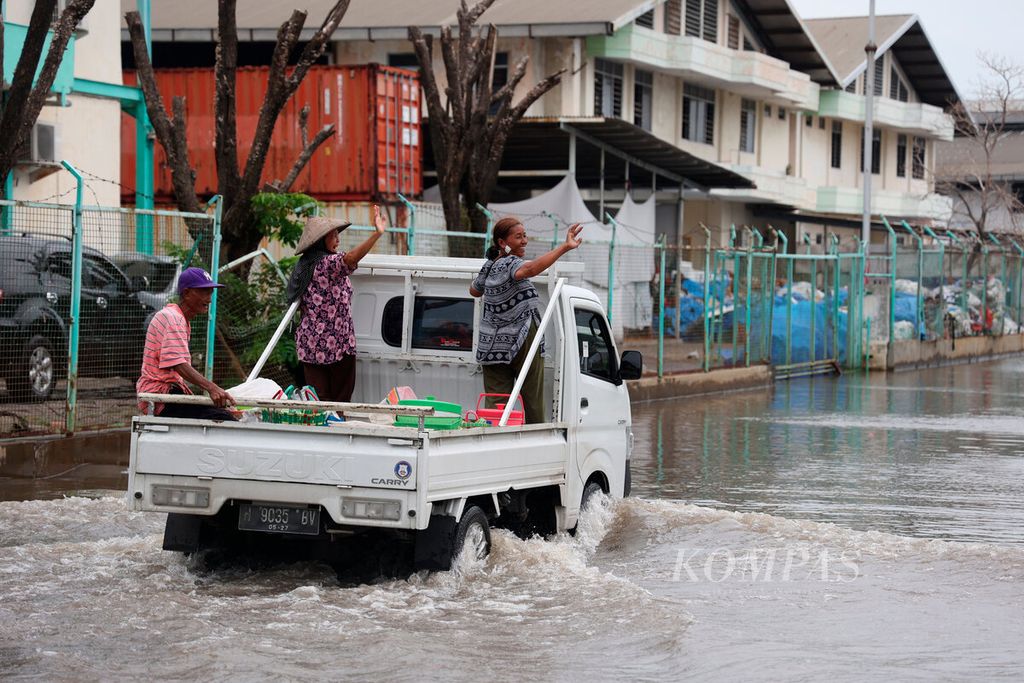 Warga melintasi genangan banjir saat melintasi kawasan berikat di Pelabuhan Tanjung Emas, Kota Semarang, Jawa Tengah, Jumat (3/2/2023). 