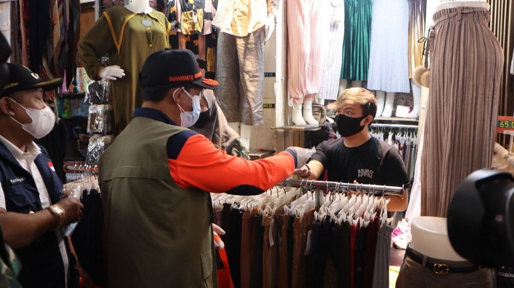Kepala Badan Nasional Penanggulangan Bencana Letnan Jenderal Suharyanto memberikan masker kepada pemilik toko di Pasar Baru, Kota Bandung, Jabar, Sabtu (19/2/2022). Kasus baru Covid-19 di Bandung hingga kini terus meningkat.