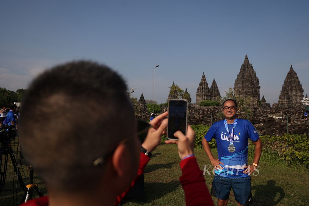 Pelari yang mencapai finis berfoto dengan medalinya seusai mengikuti lomba Mandiri Jogja Marathon 2022 di kawasan Candi Prambanan, Sleman, DI Yogyakarta, Minggu (14/8/2022). 