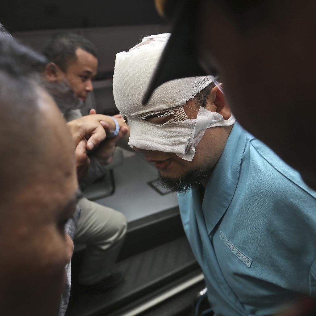 Indonesian Corruption Eradication Commission (KPK) investigator Novel Baswedan, center, who was injured in an attacked by unidentified assailants is assisted by officials and police officers as he leaves the general hospital where he was treated in to be transferred to an eye hospital, in Jakarta, Indonesia, Tuesday, April 11, 2017. Police say the anti-graft commission investigator leading a probe into a scandal that threatens to implicate high-profile Indonesian politicians was attacked with a chemical as he returned from dawn prayers. 