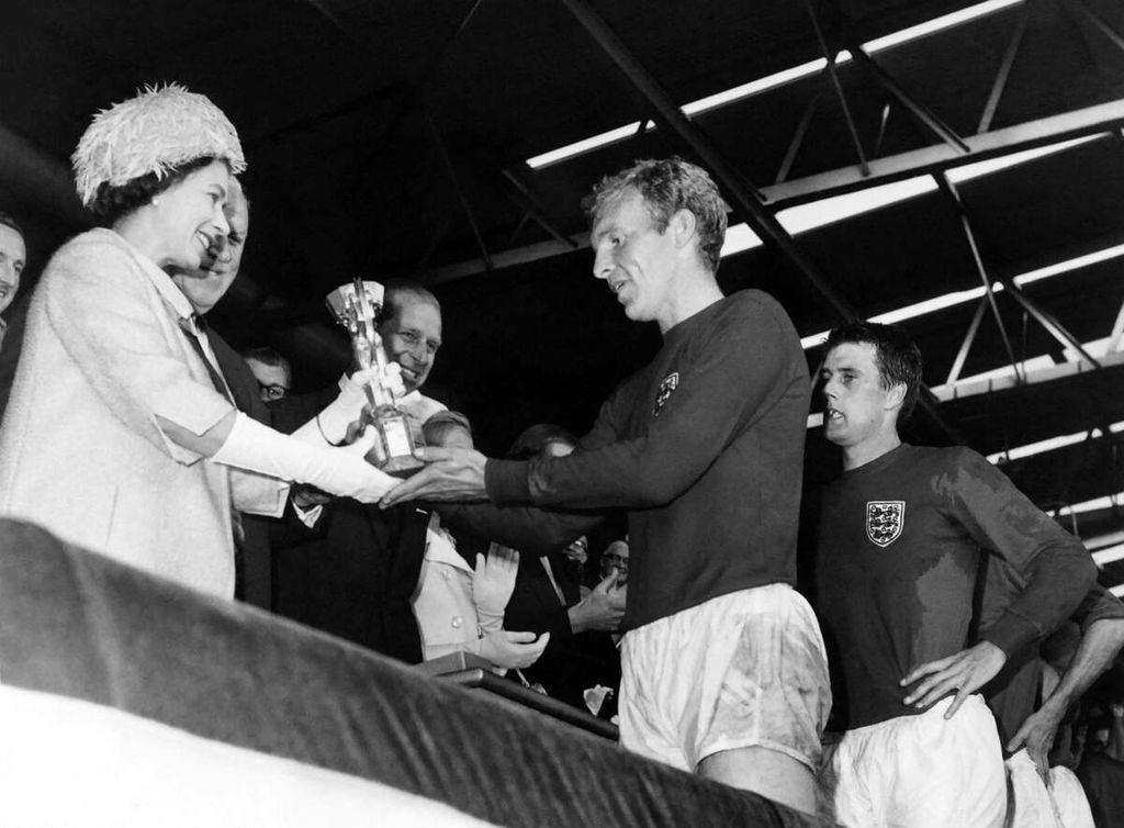 Arsip foto 30 Juli 1966 ini memperlihatkan Ratu Inggris Elizabeth II menyerahkan trofi Jules Rimet, lambang juara Piala Dunia, kepada kapten tim nasional Inggris, Bobby Moore, disaksikan Pangeran Philip, Duke of Edinburgh (kedua dari kiri), dan striker timnas Inggris, Geoff Hurst, di Stadion Wembley, London, Inggris. Inggris menjadi juara Piala Dunia 1966 setelah mengalahkan Jerman, 4-2.