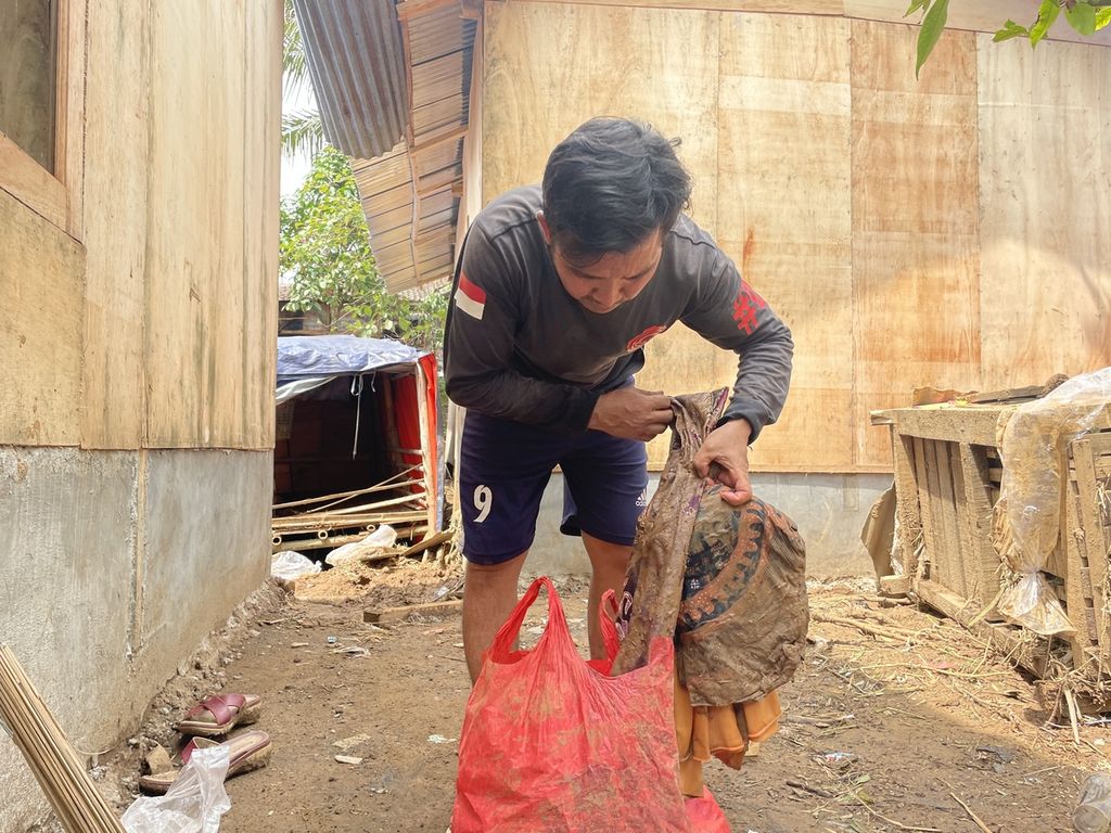 Penyintas gempa Cianjur, Dede Ramlan (40), memilah pakaian yang terendam banjir Kampung Gununglanjung RT 002 RW 007 Desa Cijedil, Kecamatan Cugenang, Kamis (23/3/2023).