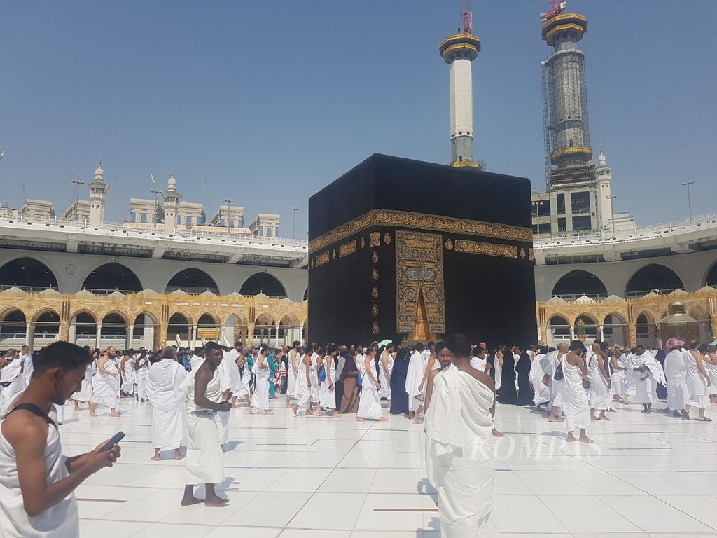 An Umrah pilgrim checks his cellphone in front of the Kaaba at the Grand Mosque, Mecca, Saudi Arabia, Friday (10/6/2022). Almost all Umrah and Hajj pilgrims now carry cell phones to take pictures of themselves in a tawaf atmosphere near the Kaaba.