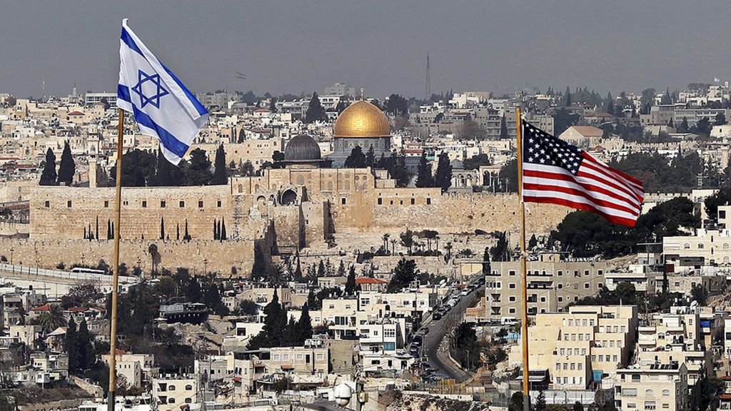 Foto yang diambil pada 13 Desember 2017 ini memperlihatkan bendera Israel dan Amerika Serikat, yang dipasang di atas atap sebuah bangunan, dengan latar belakang pemandangan permukiman Israel di Jerusalem Timur dan Kota Tua Jerusalem. Terlihat pula Masjidil Aqsa dan Kubah Batu. Arab Saudi, Sabtu (12/8/2023), menunjuk duta besarnya untuk Palestina, merangkap konsul jenderal di Jerusalem. 