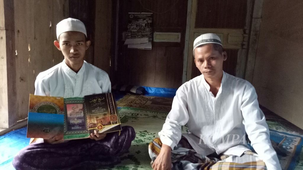 Santri Kyai Amin Fausan, Iwan (kiri), sedang menunjukkan beberapa Kitab Kuning yang menjadi kitab penting untuk dikuasai santri di pesantren, di samping kitab lainnya.