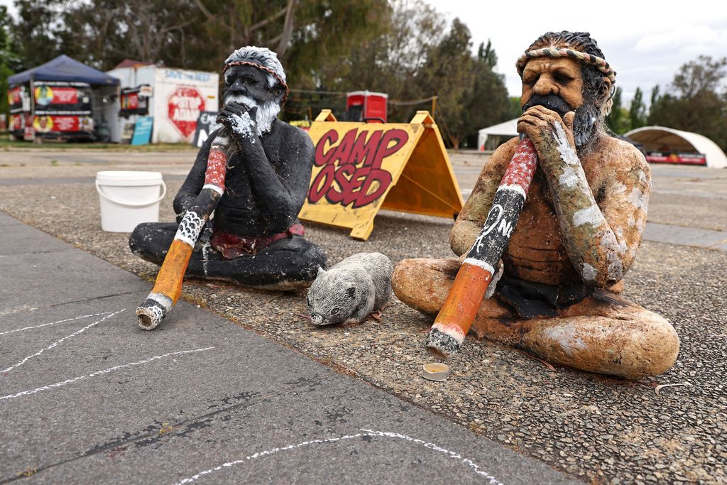 Two statues of indigenous Australians holding a didgeridoo, a musical instrument, sit in front of the Aboriginal Tent Embassy located outside the Old Parliament House in Canberra, Australia, on October 15, 2023.