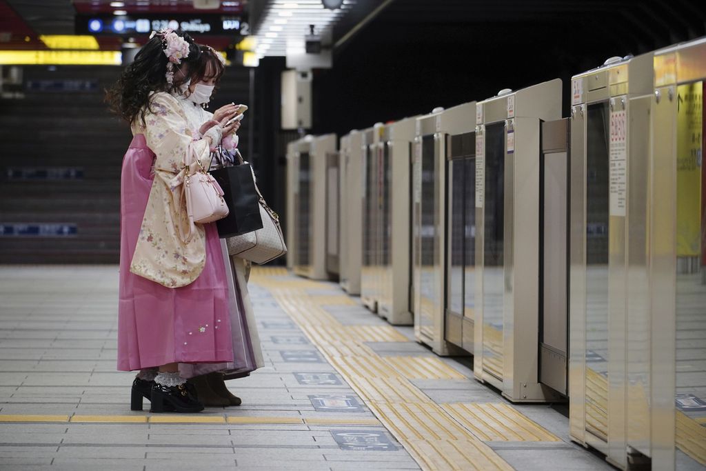 Dua perempuan mengenakan masker untuk mencegah penyebaran virus korona saat menunggu di stasiun kereta bawah tanah di Tokyo, 4 Februari 2022. 