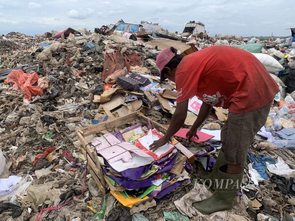 Rustam (39), salah seorang pemulung, mengikat tumpukan sampah kertas yang dikumpulkan di TPA Tamangapa, Makassar, Senin (20/9/2021). Di TPA ini, ratusan orang menggantungkan hidupnya.
