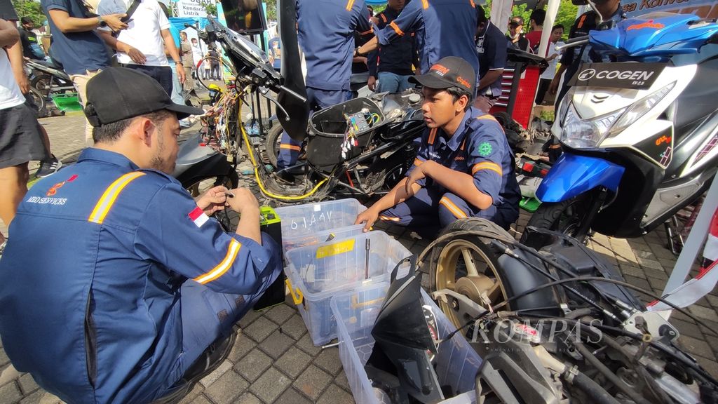 Aktivitas teknisi yang sedang mengonversi sepeda motor mesin berbahan bakar minyak (BBM) ke sepeda motor listrik pada Electric Vehicle Funday, di Plaza Timur, Gelora Bung Karno (GBK), Jakarta, Minggu (18/12/2022).  