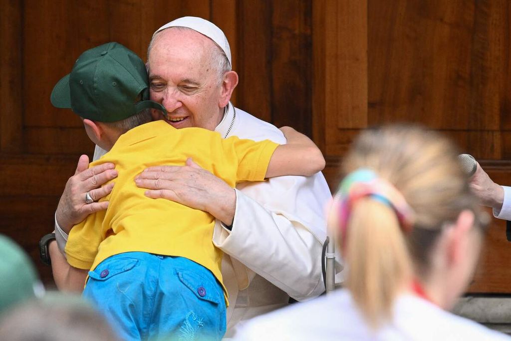 Paus Fransiskus memeluk seorang bocah pengungsi asal Ukraina pada pertemuan "The Cortile dei Bambini" atau Halaman Anak-anak dengan anak-anak yang datang dari seluruh Italia, 4 Juni 2022, di halaman San Damaso di Vatikan. (Photo by Tiziana FABI / AFP)