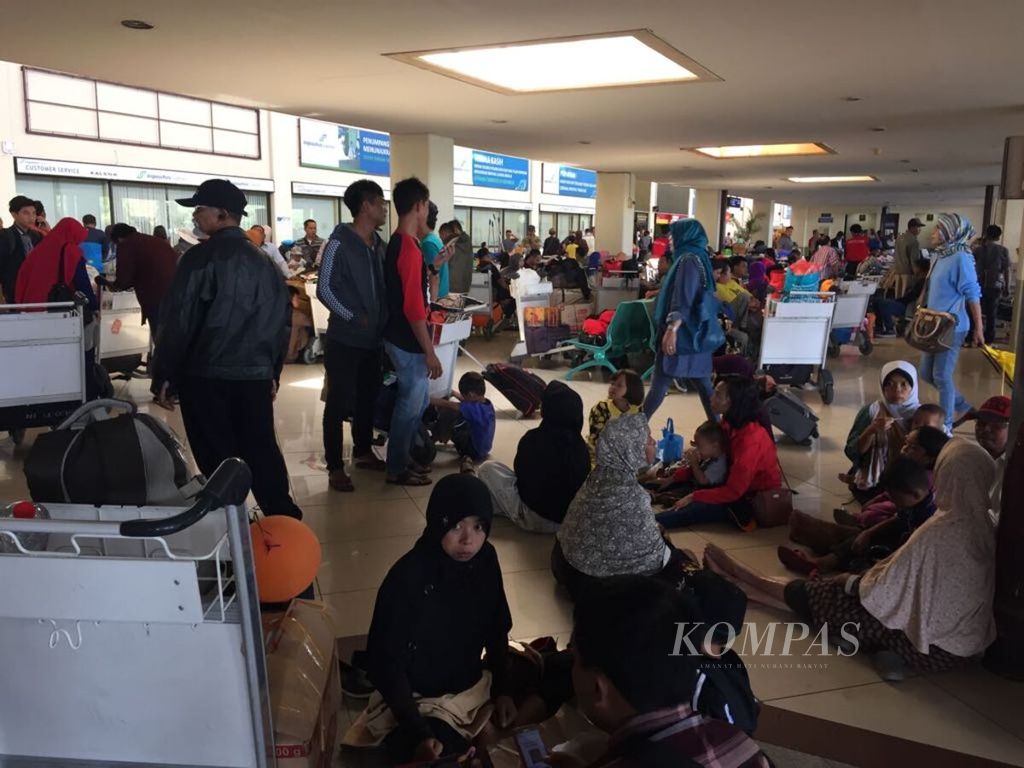 Penumpang duduk lesehan di lantai Terminal 1 Bandara Juanda menunggu kepastian jadwal penerbangan, Jumat (29/6/2018).