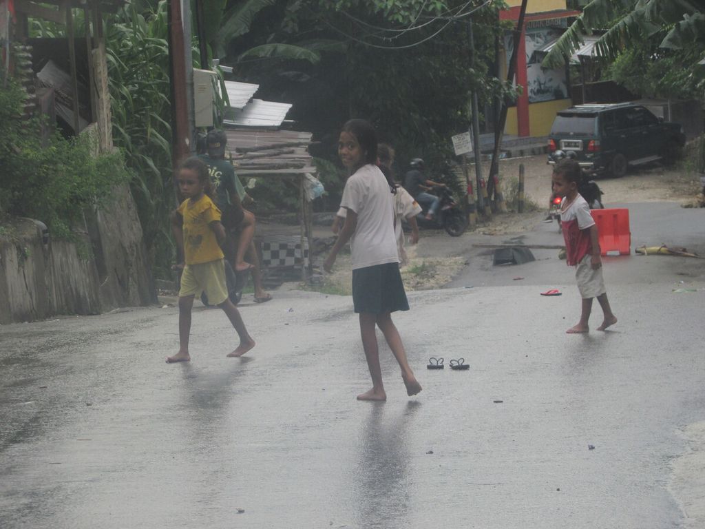 Beberapa anak sedang melintasi jalan seusai berjualan jagung rebus keliling di Kelurahan Liliba, Kota Kupang, Selasa (12/3/2024).