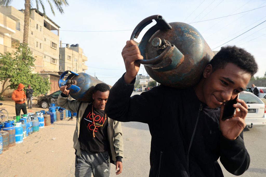 Warga membawa tabung gas kosong untuk diisi lagi dengan gas untuk memasak dari tangki bahan bakar yang masuk ke Gaza melalui penyeberangan Rafah dengan Mesir, di Rafah di selatan Jalur Gaza pada Sabtu (25/22/2023). 