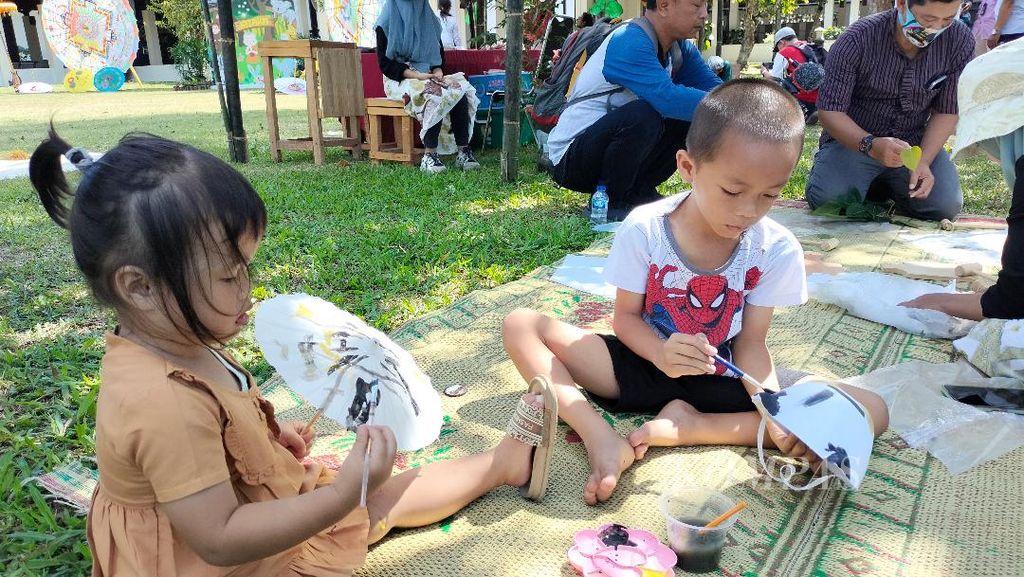 Dua wisatawan anak melukis topeng dan payung kertas di halaman Museum Kapal Samuderaraksa, Taman Wisata Candi Borobudur, Kabupaten Magelang, Jawa Tengah, Sabtu (1/7/2023). Mereka menjadi peserta paket program liburan Kumpul Bocah.