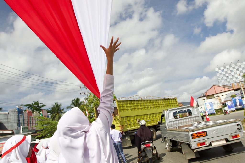 Lebih dari 18.000 siswi dan siswa SMA/SMK membentangkan bendera sepanjang 17 kilometer di Kendari, Sulawesi Tenggara, Selasa (15/8/2023). 